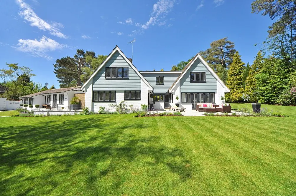 A beautifully maintained two-story house with a perfectly manicured green lawn, showcasing the pristine results of professional residential cleaning.