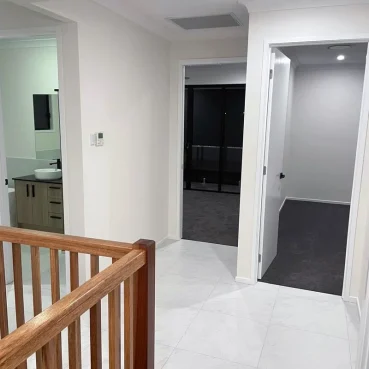 Pristine residential hallway and bedrooms after a professional deep clean. Showcasing the contrast between vacuumed dark carpets and gleaming white marble tiles, along with a spotless modern bathroom.